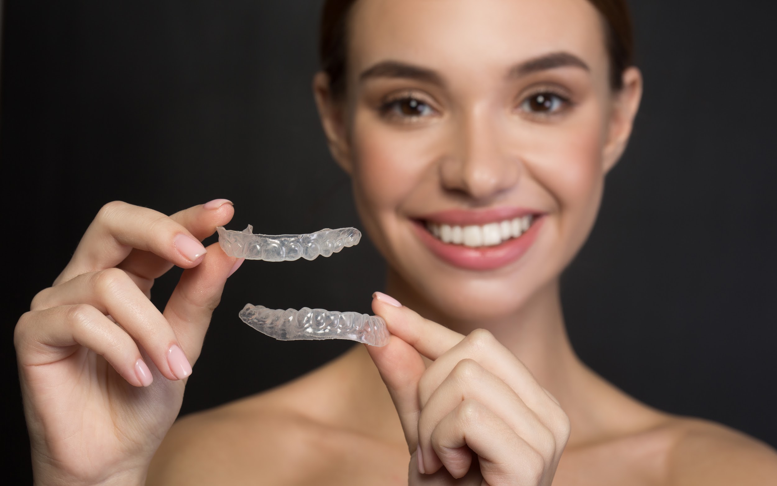 Woman holds up ClearCorrect aligners for top and bottom teeth
